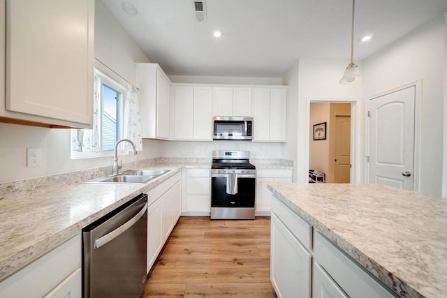 kitchen featuring light wood-type flooring, appliances with stainless steel finishes, light countertops, and a sink