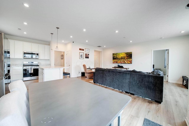 living room with light wood finished floors, baseboards, and recessed lighting