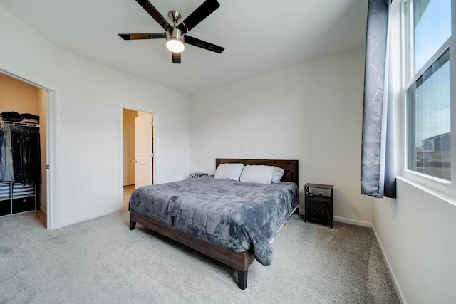 carpeted bedroom with a ceiling fan, a closet, a spacious closet, and baseboards