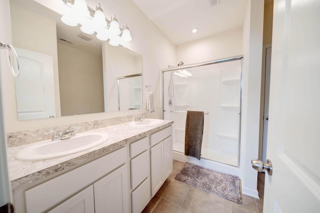 bathroom with double vanity, a stall shower, a sink, and tile patterned floors