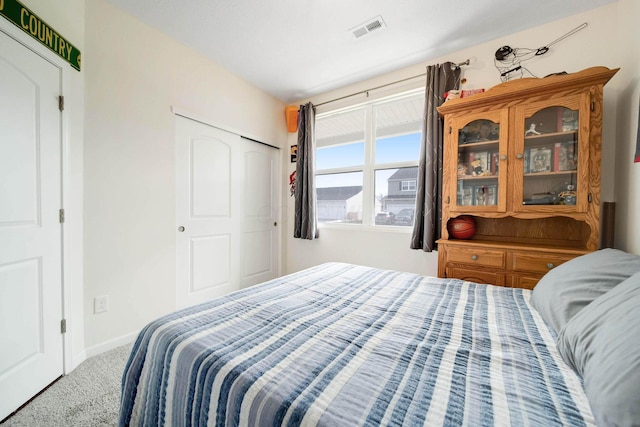 carpeted bedroom with a closet, visible vents, and baseboards