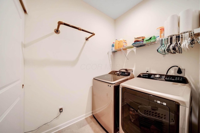 clothes washing area featuring laundry area, washing machine and dryer, and baseboards