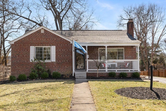 view of front of property with a chimney, fence, a front yard, a porch, and brick siding