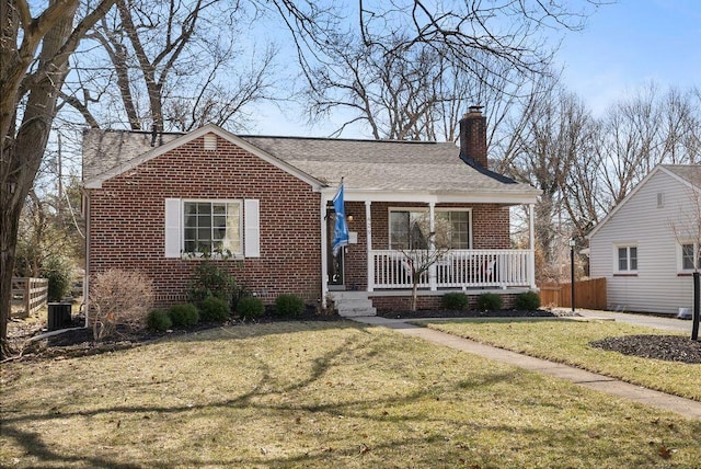 bungalow-style home with brick siding, a shingled roof, a chimney, covered porch, and a front yard