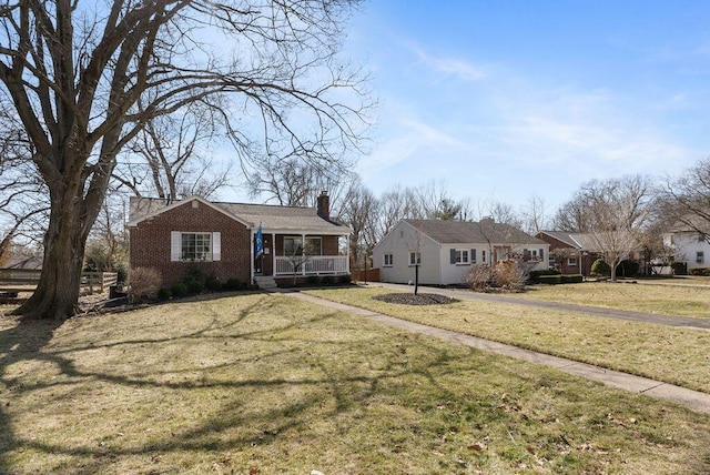 single story home featuring a chimney, brick siding, a front lawn, and a porch