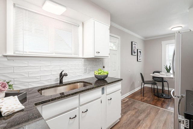 kitchen featuring a sink, white cabinetry, ornamental molding, freestanding refrigerator, and tasteful backsplash