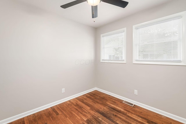 unfurnished room with ceiling fan, dark wood-style flooring, visible vents, and baseboards