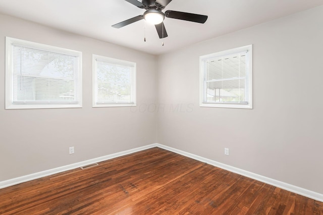 unfurnished room with a healthy amount of sunlight, dark wood-style floors, baseboards, and visible vents