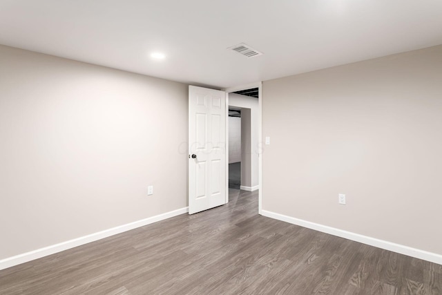 spare room featuring wood finished floors, visible vents, and baseboards