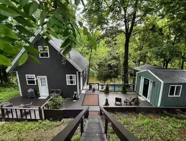 back of house with an outdoor structure and a wooden deck