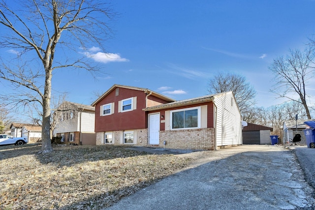 tri-level home featuring a garage, an outbuilding, and brick siding