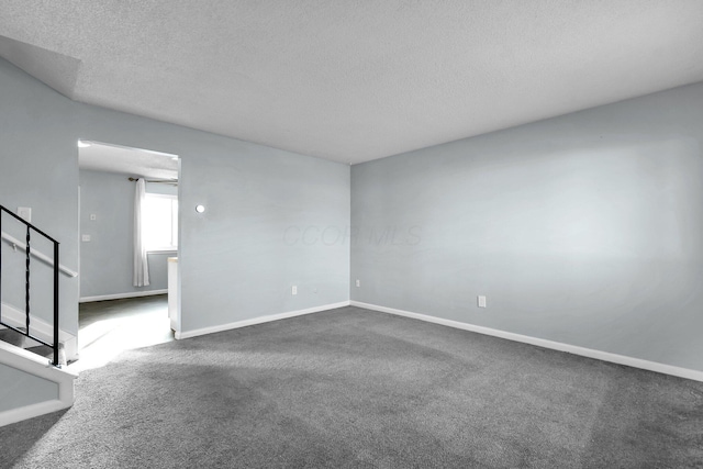 carpeted empty room with stairs, baseboards, and a textured ceiling