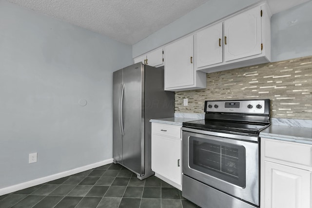 kitchen with decorative backsplash, appliances with stainless steel finishes, white cabinetry, a textured ceiling, and dark tile patterned floors