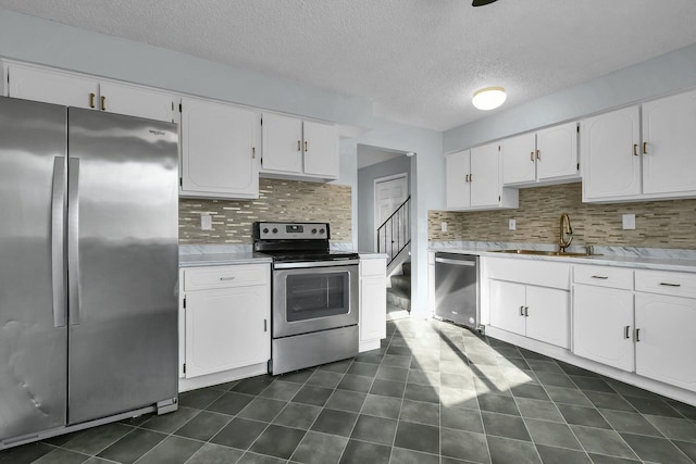 kitchen with stainless steel appliances, a sink, light countertops, and white cabinets