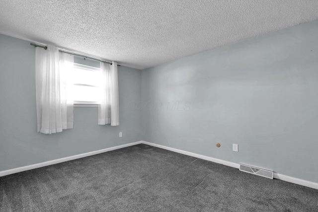 spare room with baseboards, visible vents, dark carpet, and a textured ceiling