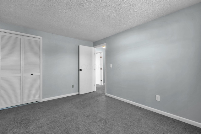 unfurnished bedroom with a textured ceiling, a closet, dark carpet, and baseboards