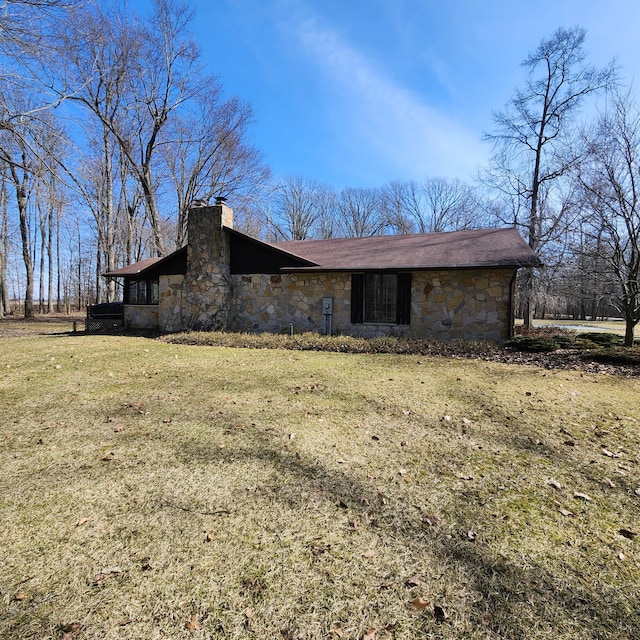 exterior space with stone siding, a chimney, and a front yard