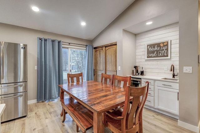 dining space with lofted ceiling, light wood finished floors, and baseboards