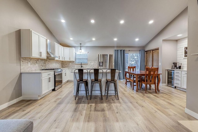 kitchen featuring lofted ceiling, beverage cooler, a kitchen island, and stainless steel appliances