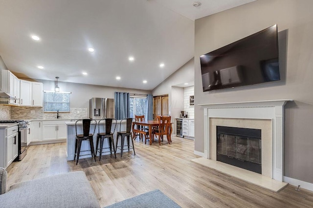 kitchen featuring beverage cooler, a breakfast bar, range with gas stovetop, stainless steel refrigerator with ice dispenser, and a center island