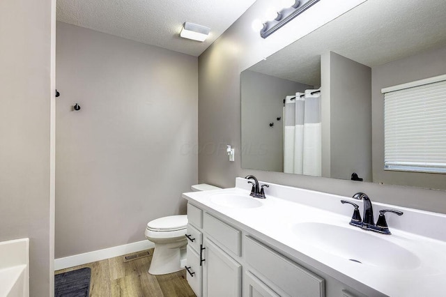 full bath featuring toilet, wood finished floors, a sink, and visible vents