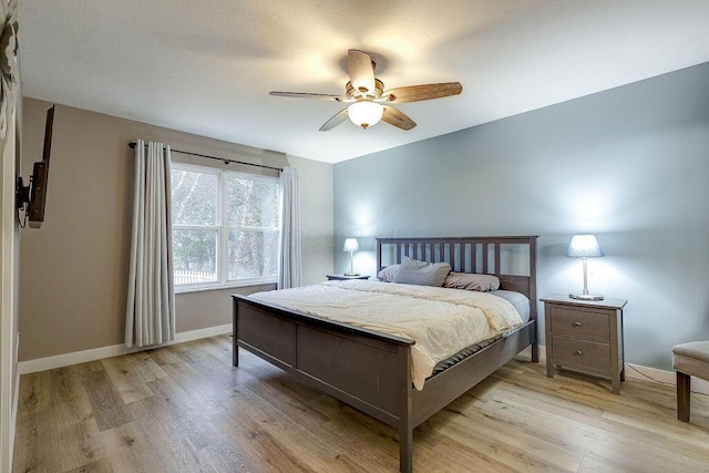 bedroom with a ceiling fan, light wood-type flooring, and baseboards