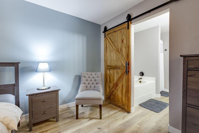 living area featuring light wood finished floors, a barn door, and baseboards