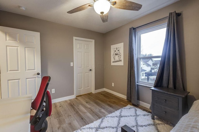 bedroom with light wood-style floors, ceiling fan, and baseboards