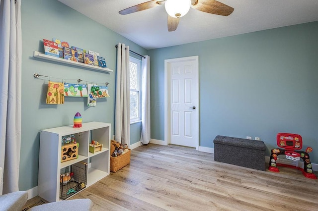 recreation room featuring wood finished floors, a ceiling fan, and baseboards