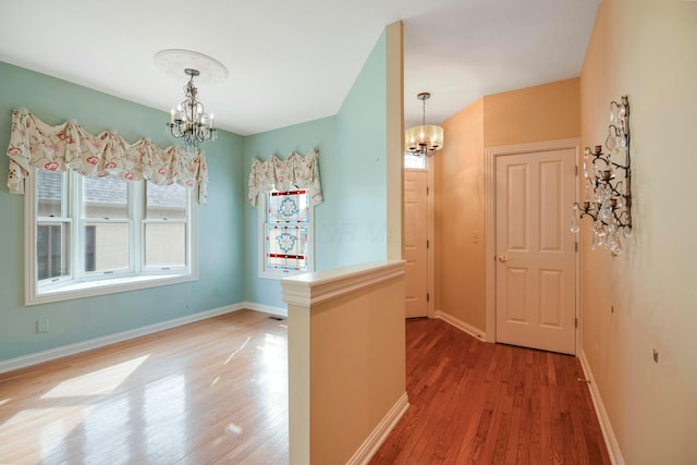 interior space with a chandelier, wood finished floors, and baseboards