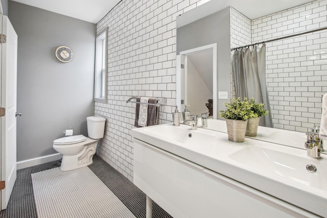 bathroom with toilet, a sink, tile patterned flooring, and tile walls