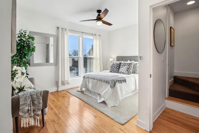 bedroom with a ceiling fan, hardwood / wood-style flooring, and baseboards