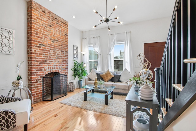 living area featuring stairs, a fireplace, a chandelier, and hardwood / wood-style flooring