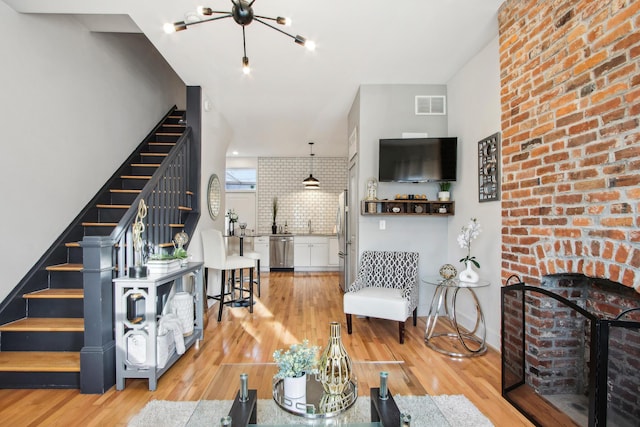 living area with light wood finished floors, stairway, visible vents, and baseboards