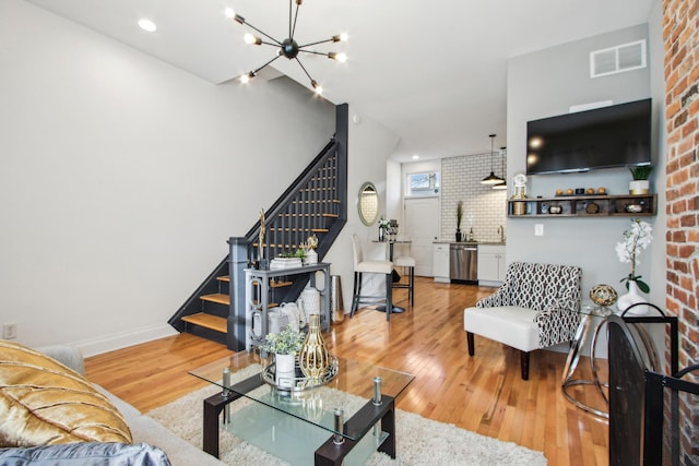 living room with light wood finished floors, baseboards, visible vents, stairs, and a chandelier