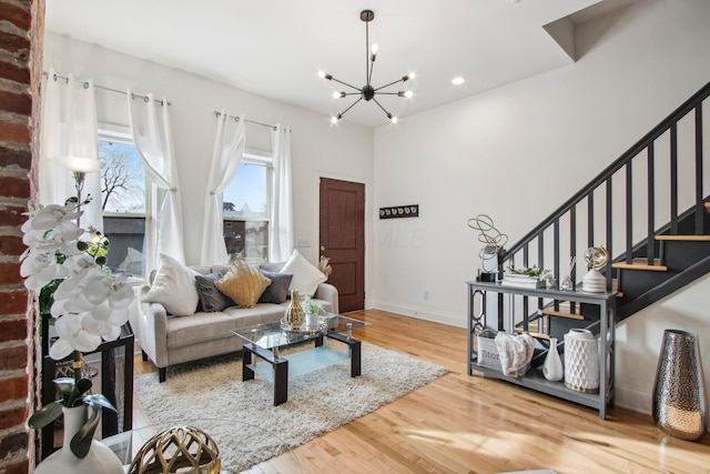 living room featuring baseboards, stairway, wood finished floors, and a notable chandelier