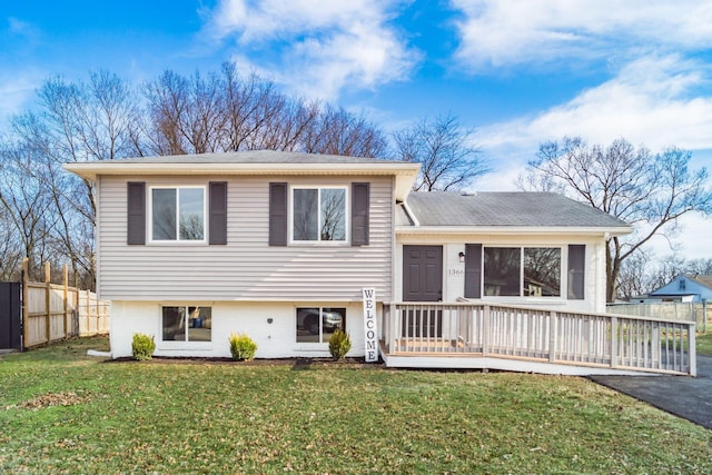 tri-level home featuring aphalt driveway, a front yard, fence, and a wooden deck