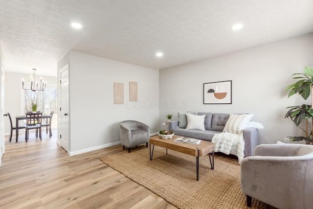 living area featuring light wood-style floors, baseboards, a chandelier, and recessed lighting