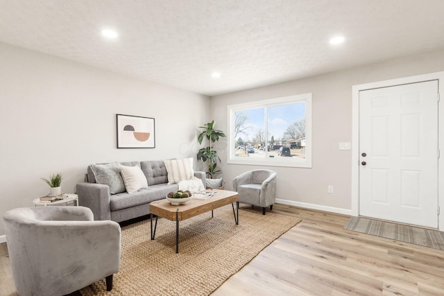 living area with recessed lighting, light wood-style flooring, baseboards, and a textured ceiling