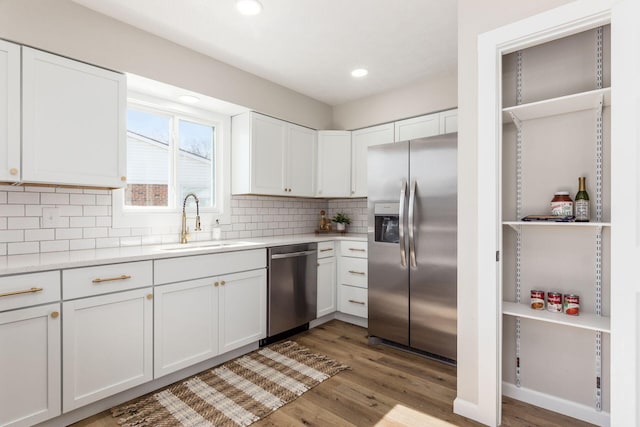 kitchen with light countertops, appliances with stainless steel finishes, a sink, and decorative backsplash