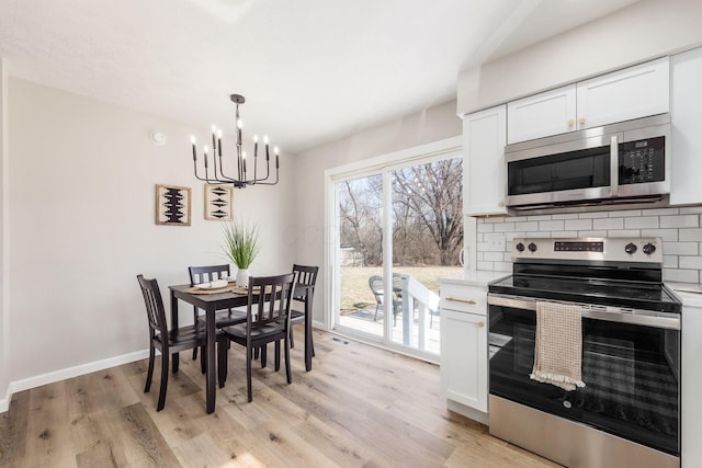 dining space with light wood finished floors, baseboards, and an inviting chandelier