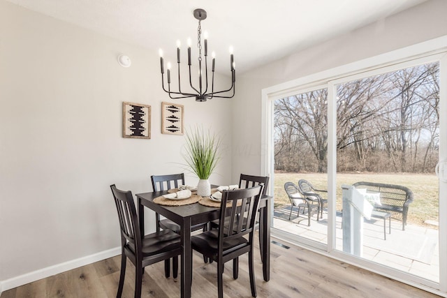 dining space with baseboards, an inviting chandelier, and light wood-style floors