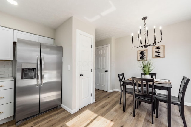 dining space featuring light wood-type flooring, an inviting chandelier, and baseboards