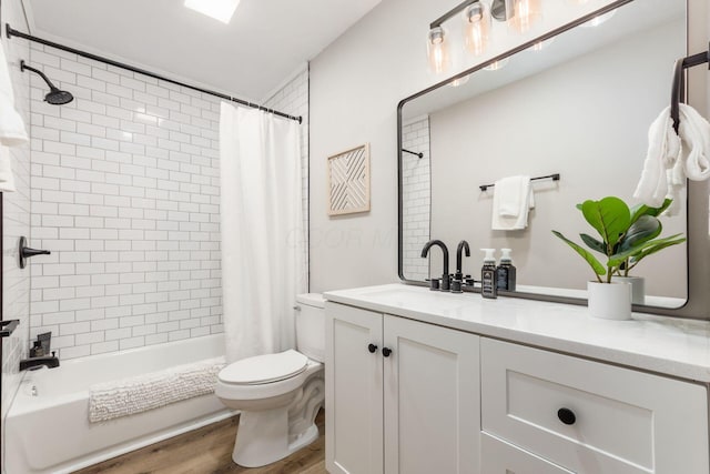 bathroom featuring toilet, shower / bath combo with shower curtain, wood finished floors, and vanity