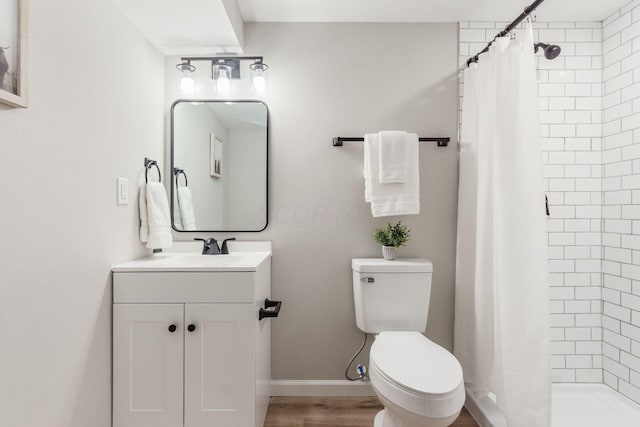 full bathroom with toilet, a stall shower, baseboards, and vanity