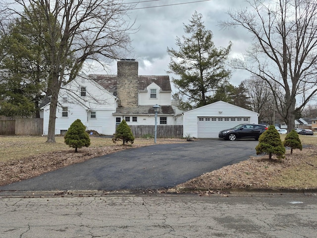 view of front of home featuring a garage, a chimney, an outdoor structure, and fence