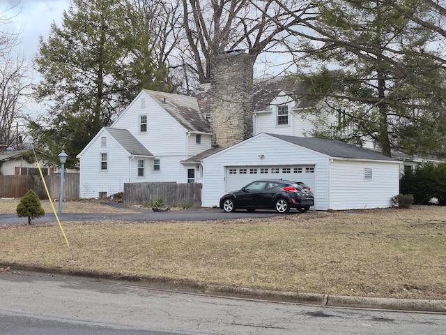 exterior space with a garage, an outbuilding, fence, and a front yard