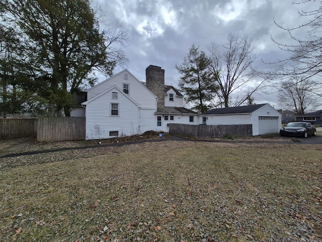 view of property exterior featuring a chimney, an outdoor structure, and fence