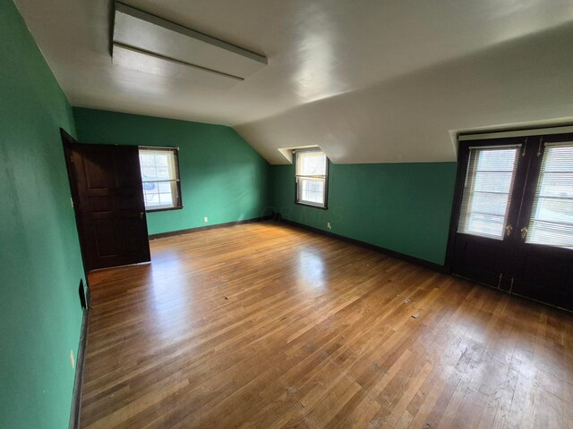 bonus room featuring lofted ceiling, wood-type flooring, baseboards, and plenty of natural light