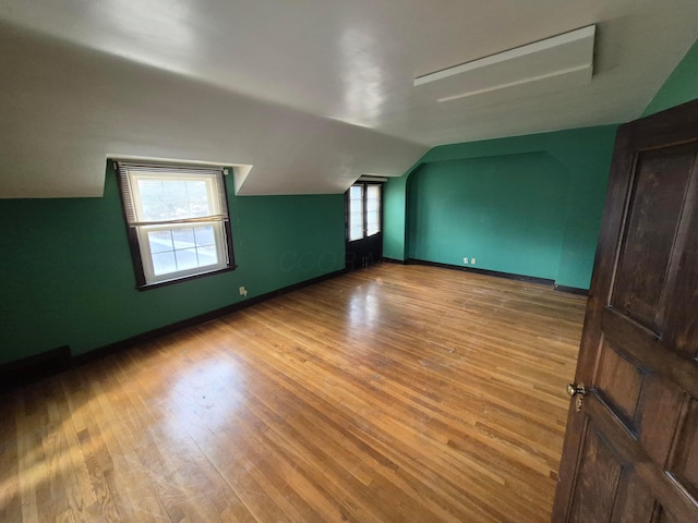 additional living space with a healthy amount of sunlight, vaulted ceiling, and wood finished floors